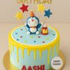 Doremon theme birthday cake by Sweet Cakery with yellow cream drips, fondant Doremon topper, colourful stars, gift box, and Happy Birthday topper
