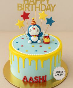 Doremon theme birthday cake by Sweet Cakery with yellow cream drips, fondant Doremon topper, colourful stars, gift box, and Happy Birthday topper