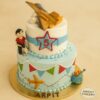 Two-tier fighter jet theme birthday cake with fondant jet, star badge, bunting, and boy figurine, created by Sweet Cakery in Bangalore