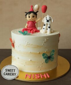 Girl with puppy theme birthday cake from Sweet Cakery, featuring a doll topper in red dress, cute puppy figurine, balloons, butterflies, and pearl accents on cream finish.