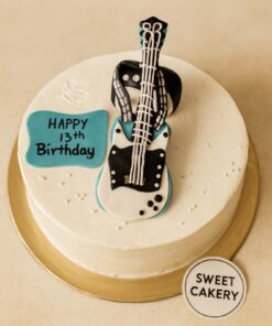 Round cream cake with black and white fondant electric guitar topper for music-themed birthday