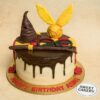 Harry Potter birthday cake by Sweet Cakery featuring cream finish, Sorting Hat, Golden Snitch, wand, glasses, and Gryffindor scarf on top