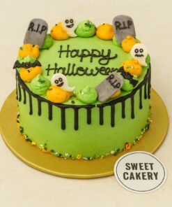 A spooky green Haunting Halloween Cake from Sweet Cakery with ghost toppers, tombstones, and black drip design, styled for festive celebrations.