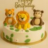 Jungle theme birthday cake with fondant lion, tiger and monkey toppers, decorated with green leaves and white flowers from Sweet Cakery Bangalore
