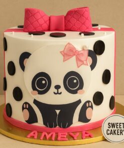 Tall panda theme birthday cake with pink bow, black polka dots, and smooth cream finish, placed on gold board