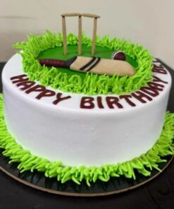 Cricket-themed birthday cake with green grass piping, edible bat, ball, and stumps