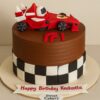 Formula 1 racing theme birthday cake with red race car topper, checkerboard fondant design, and Sweet Cakery sticker in Bangalore.