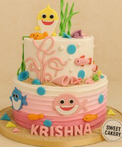 Two-tier Baby Shark theme cake with cream finish, pink-blue ombre base, fondant sharks, sea creatures, seaweed