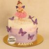 A round pastel cream cake with a fairy doll topper, purple butterflies, and gold accents, made by Sweet Cakery in Bangalore for a butterfly-themed birthday