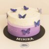 Two-layer lavender and white butterfly birthday cake with sugar pearls and purple 3D butterflies.