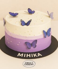 Two-layer lavender and white butterfly birthday cake with sugar pearls and purple 3D butterflies.