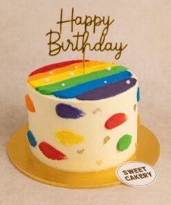 Colourful rainbow theme birthday cake from Sweet Cakery with cream finish, rainbow stripes, brushstroke details, gold accents, and topper.