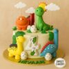 Dinosaur theme birthday cake from Sweet Cakery featuring colourful fondant dinosaurs, eggs, jungle leaves, and sun on a round cake