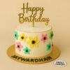 Floral cream birthday cake with hand-crafted pastel flowers, golden topper, and Sweet Cakery branding, designed for kids in Bangalore