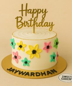 Floral cream birthday cake with hand-crafted pastel flowers, golden topper, and Sweet Cakery branding, designed for kids in Bangalore