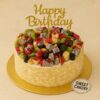 Round fruit overloaded birthday cake topped with kiwi, grapes, dragon fruit, pomegranate and apples, almond-coated sides