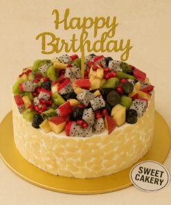 Round fruit overloaded birthday cake topped with kiwi, grapes, dragon fruit, pomegranate and apples, almond-coated sides