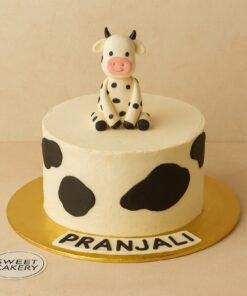 Cow theme birthday cake with fondant cow topper and black spots, custom Sweet Cakery design in Bangalore